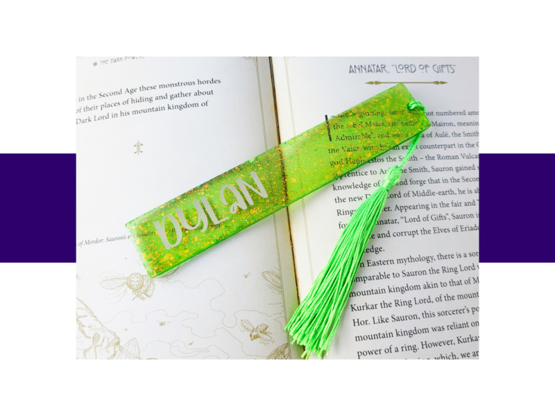 Open book with a bright green glitter bookmark and matching tassel laid diagonally across the pages.