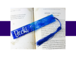 KXK-RBMK-13 Open book with gold decorative margins, a blue glittery bookmark and a blue tassel resting across the pages.