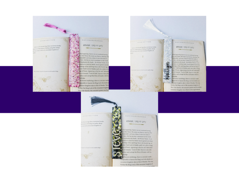 Two open books with patterned tassel bookmarks resting across the pages, set against a purple backdrop.