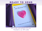 Greeting card reading 'Just Because Hug' with a glittery pink heart on white paper, framed by yellow and purple borders.