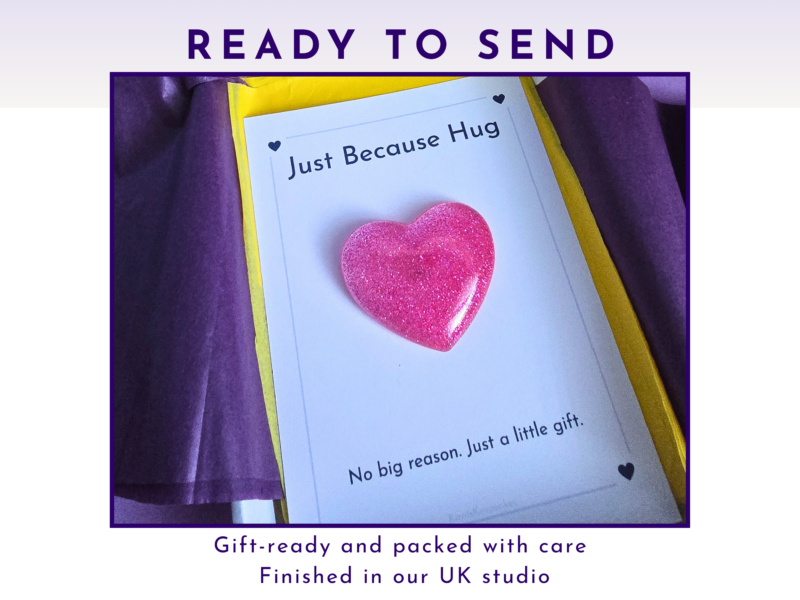 Greeting card reading 'Just Because Hug' with a glittery pink heart on white paper, framed by yellow and purple borders.