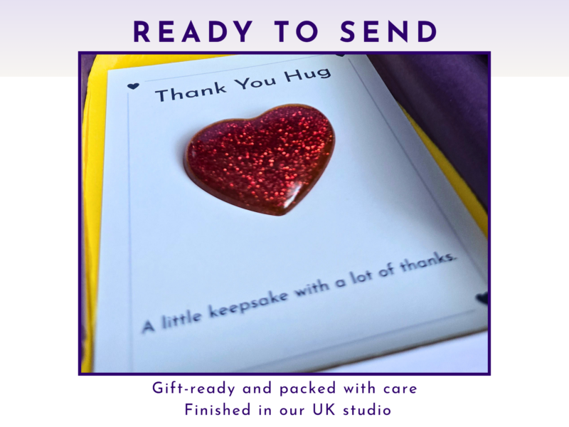 Close-up of a card showing a glittery red heart and the words 'Thank You Hug' on a page inside a gift package, suggesting a thoughtful keepsake gift