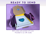 Gift box with purple wrapping and a card reading 'Thinking of You' on a purple background, ready to send.