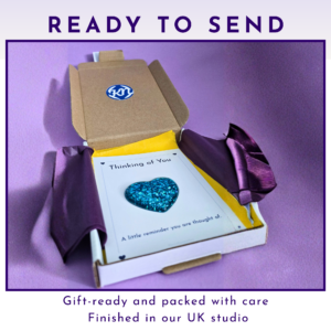Gift box with purple wrapping and a card reading 'Thinking of You' on a purple background, ready to send.