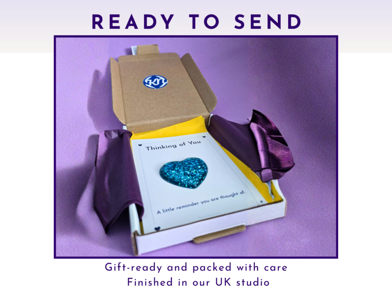 Gift box with purple wrapping and a card reading 'Thinking of You' on a purple background, ready to send.
