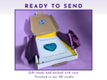 Gift box with purple wrapping and a card reading 'Thinking of You' on a purple background, ready to send.