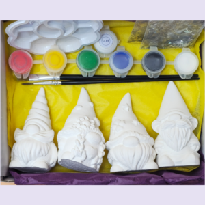 White ceramic figurines arranged with a paint set (red, yellow, green, blue, gray, white), glue, and brushes on a yellow craft tray