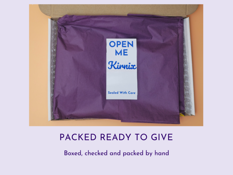 Purple tissue-wrapped package inside an open cardboard box with a white 'OPEN ME' label in blue.