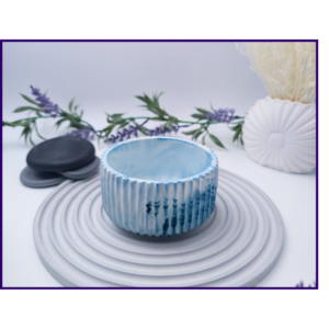 Small blue and white marbled decorative pot styled on a striped surface with neutral décor