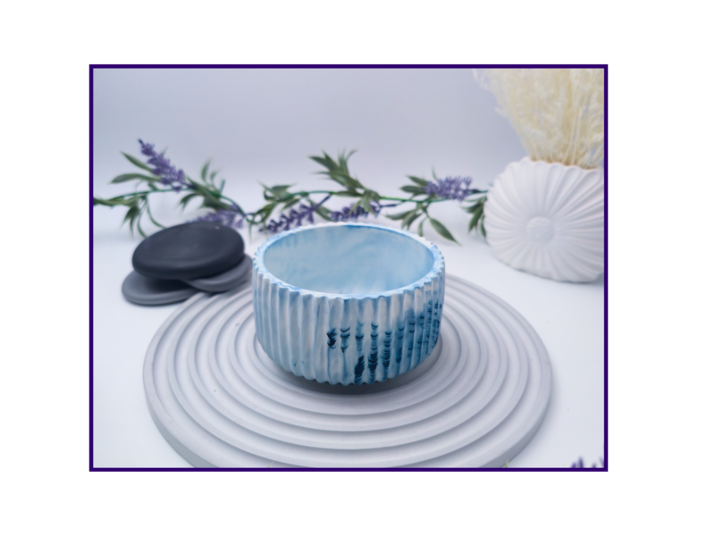 Small blue and white marbled decorative pot styled on a striped surface with neutral décor