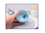 Hand holding a small blue and white marbled decorative pot to show the open top and interior