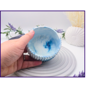 Hand holding a small blue and white marbled decorative pot to show the open top and interior