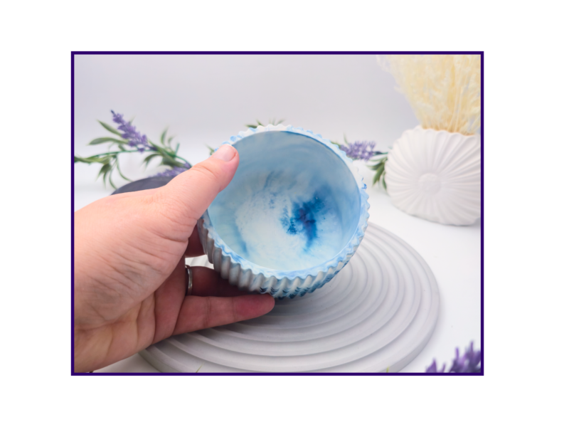 Hand holding a small blue and white marbled decorative pot to show the open top and interior