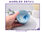 Hand holding the pot close up to show the blue and white marbled interior detail