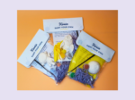 Kirnix Paint Your Own craft kit contents spread on an orange surface, with instruction cards and paints visible