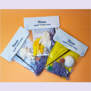 Kirnix Paint Your Own craft kit contents spread on an orange surface, with instruction cards and paints visible