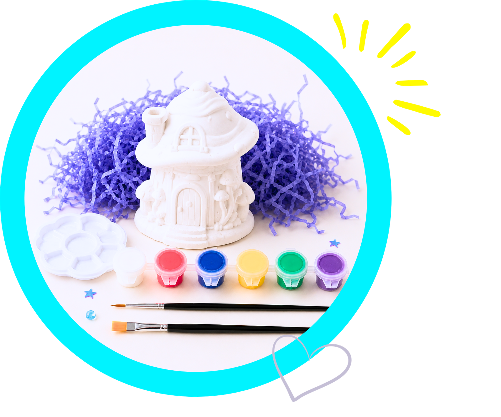 White clay house sculpture resting on purple shredded filler with a row of colorful watercolor paints and brushes nearby.