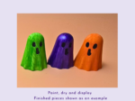 Three ghost-shaped wooden figures painted green, purple, and orange, standing side by side on a peach background.