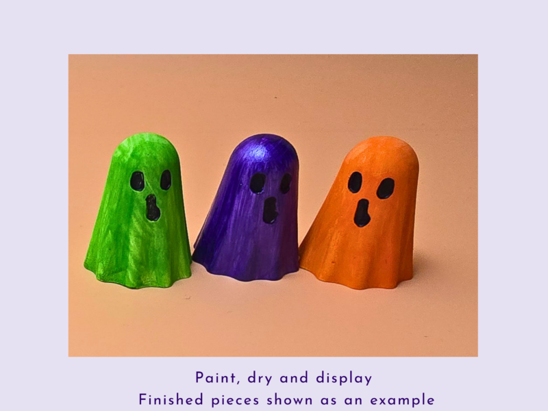 Three ghost-shaped wooden figures painted green, purple, and orange, standing side by side on a peach background.