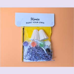 Kirnic Paint Your Own art kit with paints and ceramic shapes in a clear bag on an orange background
