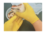 Gloved hand in yellow gloves shaping a marbled white-and-brown icing swirl in a round mold or bowl.