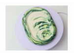 Oval object with a green marble pattern resting on a pale lavender plate, viewed from above.