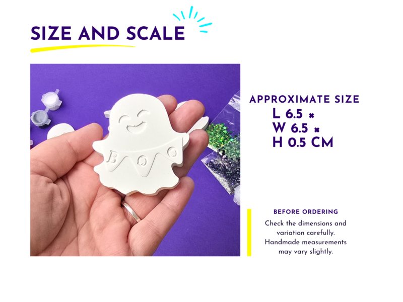 Close-up of a hand holding a small white ghost-shaped craft cutout with a smiling face on a purple background.