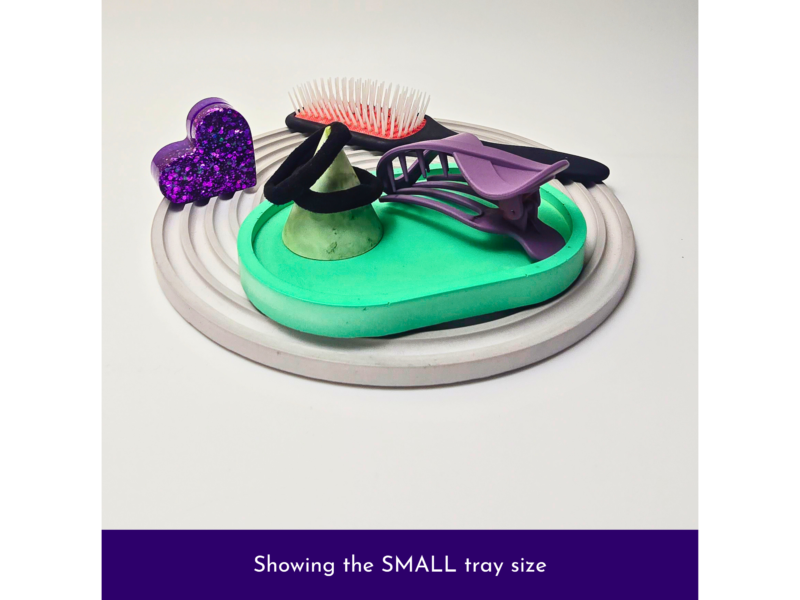 Close-up of a cake with colorful fondant decorations: a glittery purple heart, green cone, purple shapes, and pink bristle topper on a teal base.