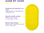 Promotional image showing a bright yellow item with purple text: 'MADE BY HAND' and feature lines describing hand-poured AquaCast eco resin and durable everyday use.