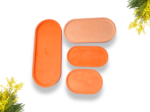 Orange pill organizers of different sizes laid out on a white background with yellow flowers in the corners.