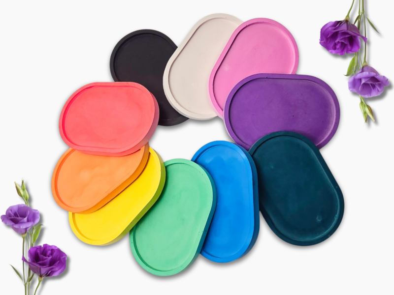 Decorative flat lay of overlapping rainbow-colored round coasters on a white background with purple flowers at the edges.