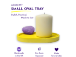 Aquacast Small Oval Tray advertisement showing a tall candle on a yellow pedestal with purple branding text on white background.