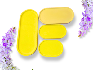 Close-up of bright yellow metal tins arranged on a white background with purple flowers along the edges.