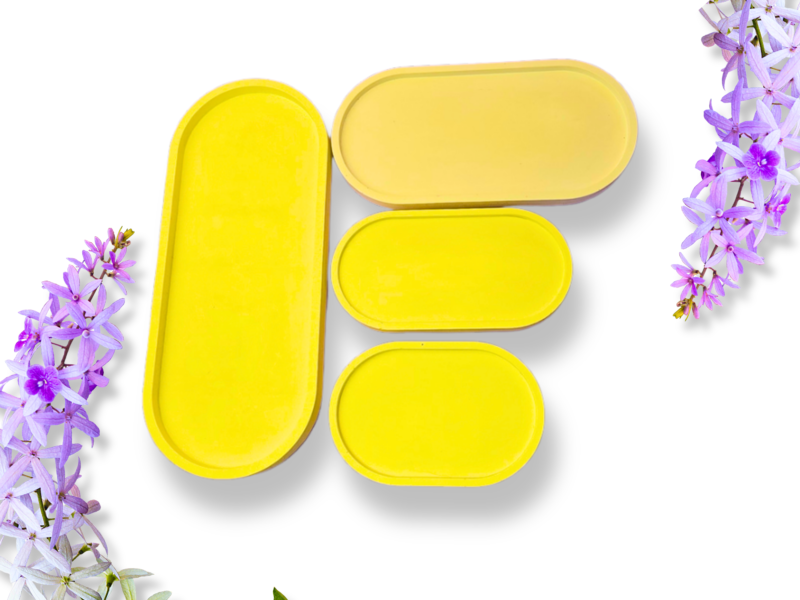 Close-up of bright yellow metal tins arranged on a white background with purple flowers along the edges.