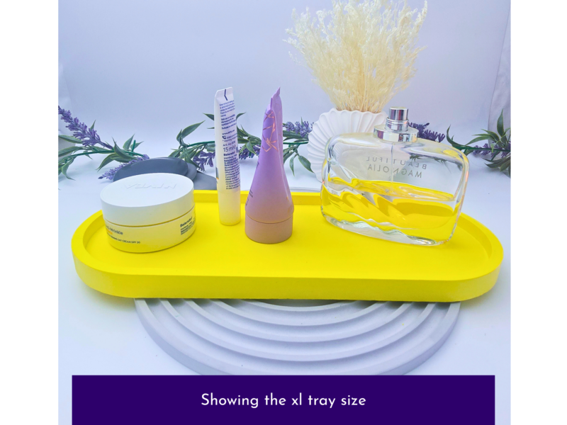 Assorted skincare and fragrance items arranged on a bright yellow tray with lavender sprigs and a clear perfume bottle against a plain background.