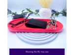 Red oval tray holds a black wallet, keys on a keyring, and glasses, with decorative lavender and a white shell behind them.