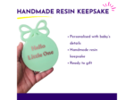 Mint personalised resin baby keepsake held in hand showing gold lettering and bow shape
