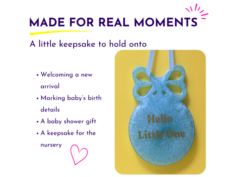 Blue resin new baby keepsake displayed hanging by its ribbon loop