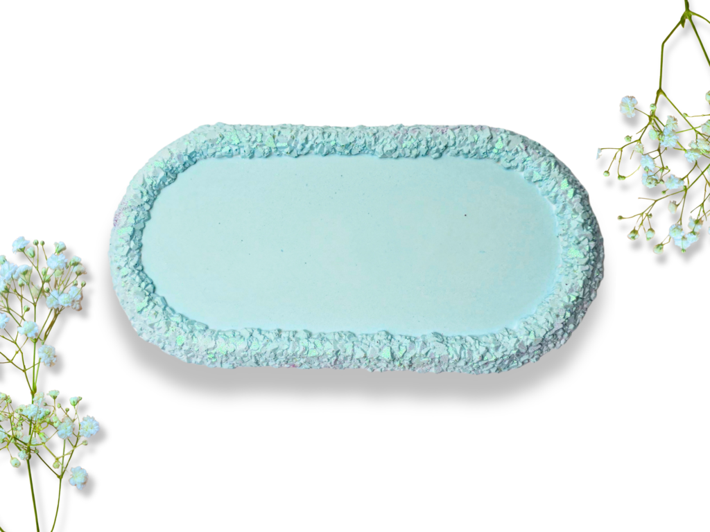 Handmade blue elongated trinket tray with a smooth centre and raised, textured druzy crystal-effect edge, photographed from above against a white background.