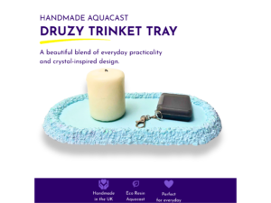 Blue handmade AquaCast vanity tray holding a cream candle and small dark accessories, showing its elongated shape and shimmering crystal-effect rim.